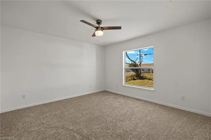 Spare room featuring ceiling fan, carpet floors, and baseboards
