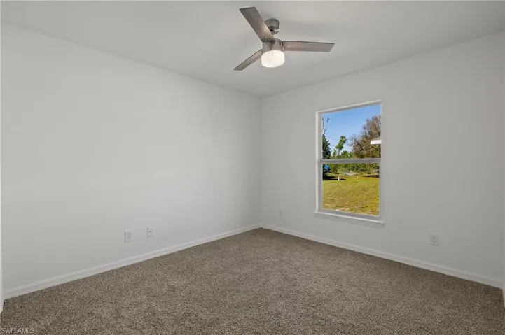 Spare room with ceiling fan, baseboards, and carpet flooring