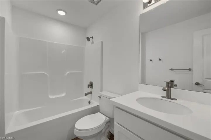 Full bath with toilet, visible vents, bathtub / shower combination, and vanity
