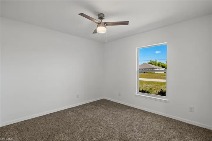 Spare room featuring carpet flooring, a ceiling fan, and baseboards