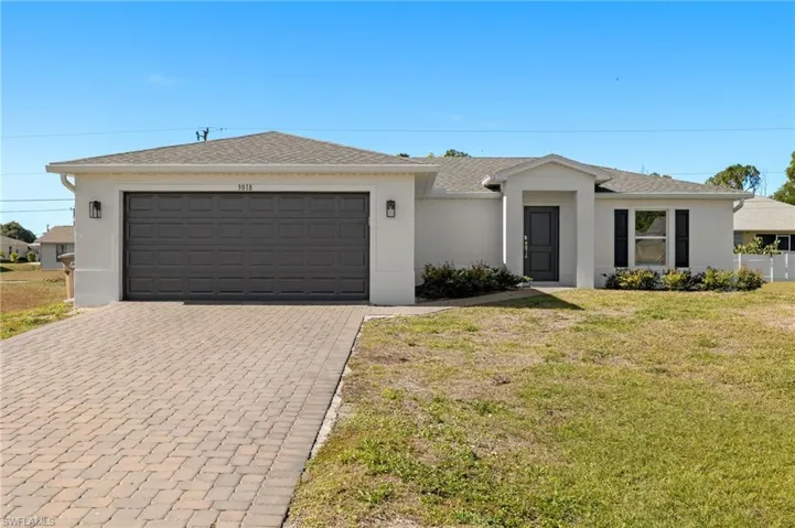 View of front of property featuring an attached garage, a front lawn, decorative driveway, and stucco siding