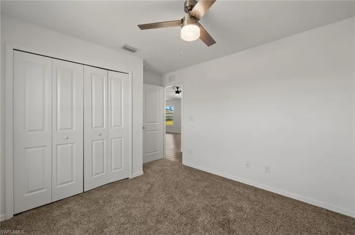 Unfurnished bedroom featuring carpet flooring, a ceiling fan, visible vents, baseboards, and a closet
