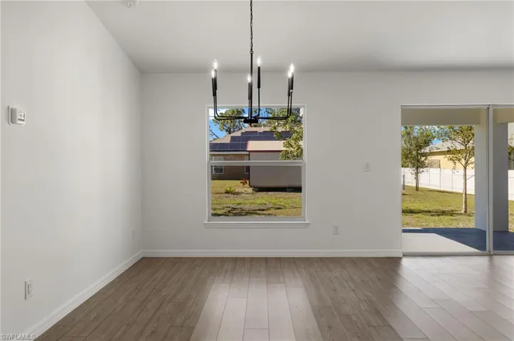 Unfurnished dining area featuring baseboards, wood finished floors, and an inviting chandelier