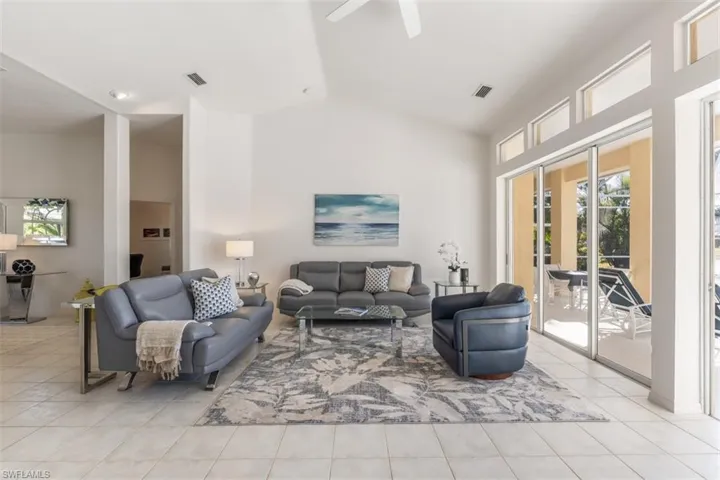 Living room featuring ceiling fan, lofted ceiling, and light tile patterned floors