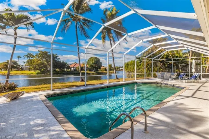 Swimming pool featuring a sunroom, glass enclosure, a patio, and a water view