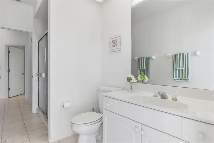 Guest full bathroom with a shower stall, vanity, and light tile patterned floors