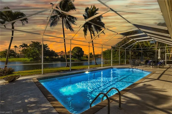 Pool area at dusk featuring an outdoor pool, western water view