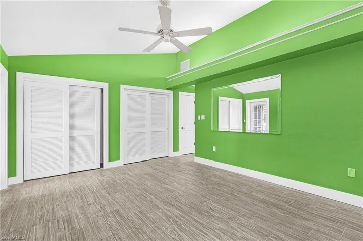 Primary Bedroom featuring wood-finish flooring, white louvered bifold closet doors, and a ceiling fan