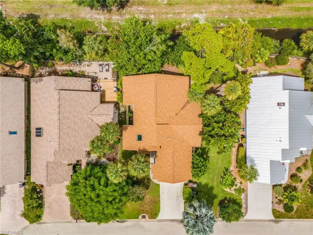 Gable roofline with skylight, mature landscaping, paved driveway, and established trees