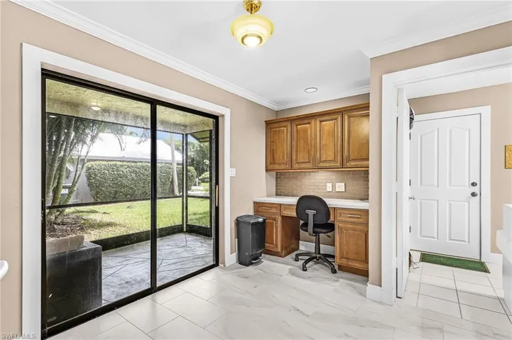 Sliding glass doors to a screened patio, built-in wooden cabinetry with a white countertop, and tiled flooring