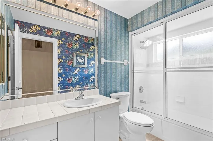 Bathroom featuring a white vanity with tile countertop, integrated sink, and white cabinetry