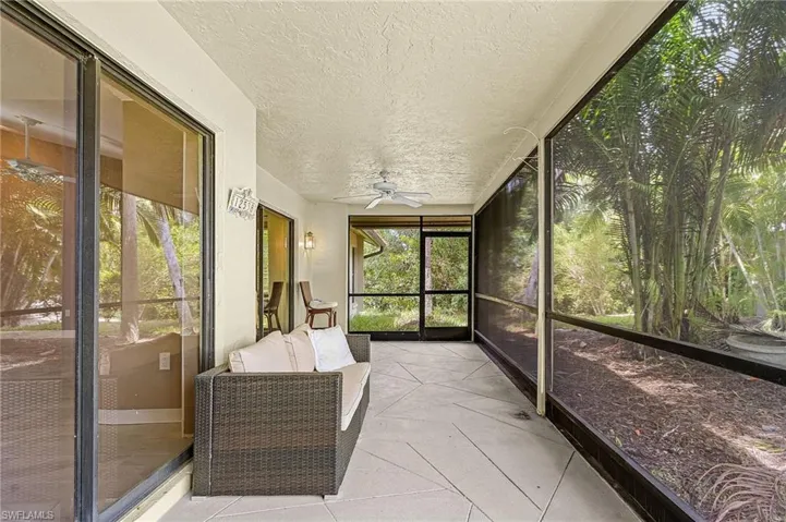 Screened patio with large format tile flooring, ceiling fan, and sliding glass doors
