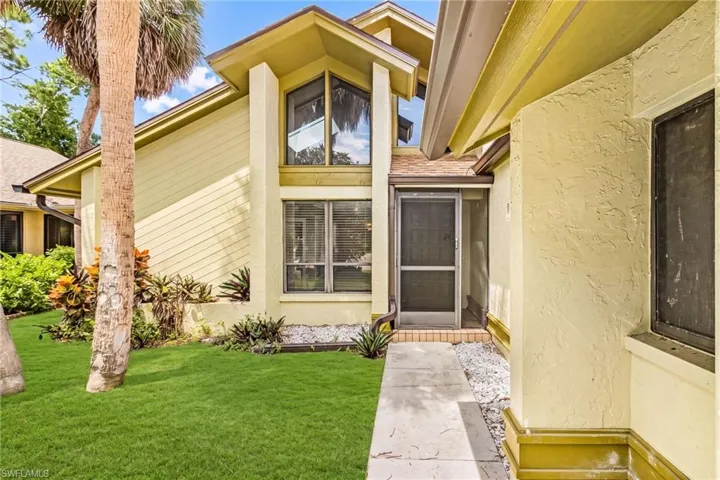 Stucco exterior with multi-pane windows and a screened entry