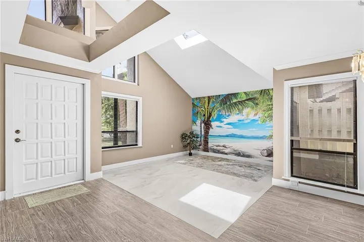 Vaulted ceiling, skylight, varied window placement, wood-finish flooring, and a decorative wall mural