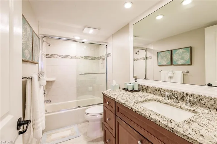 Bathroom with recessed lighting, toilet, shower / bath combination with glass door, vanity, and tile patterned floors