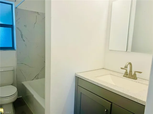 Full bathroom featuring toilet, vanity, and tiled shower / bath
