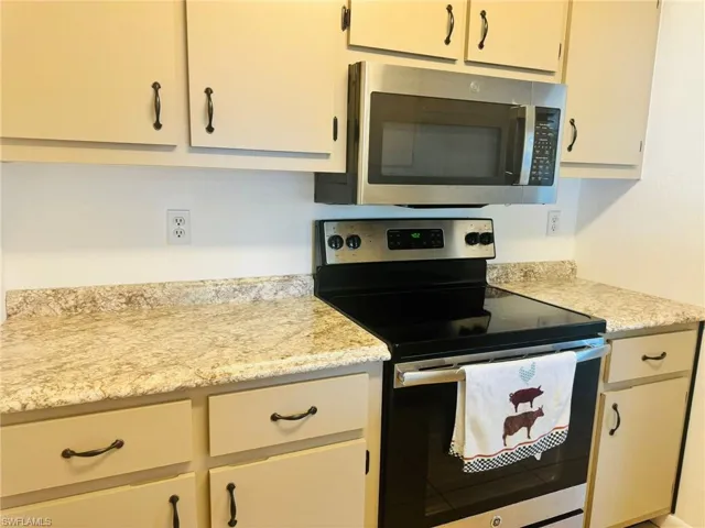 Kitchen with appliances with stainless steel finishes and light stone counters