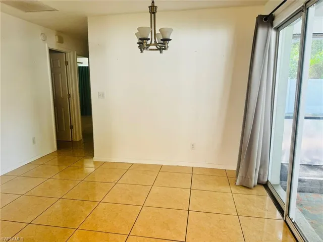 Spare room with a chandelier and light tile patterned floors