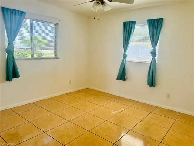 Tiled spare room featuring ceiling fan