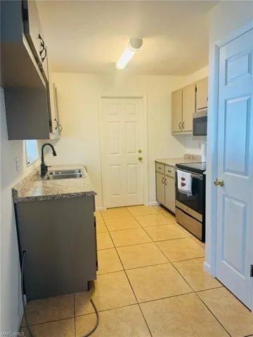 Kitchen with light tile patterned flooring, sink, and stainless steel appliances