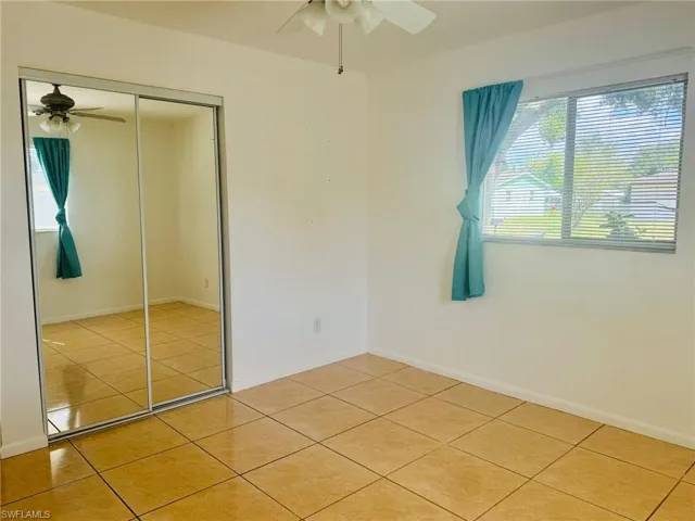 Unfurnished bedroom with light tile patterned flooring, a closet, and ceiling fan