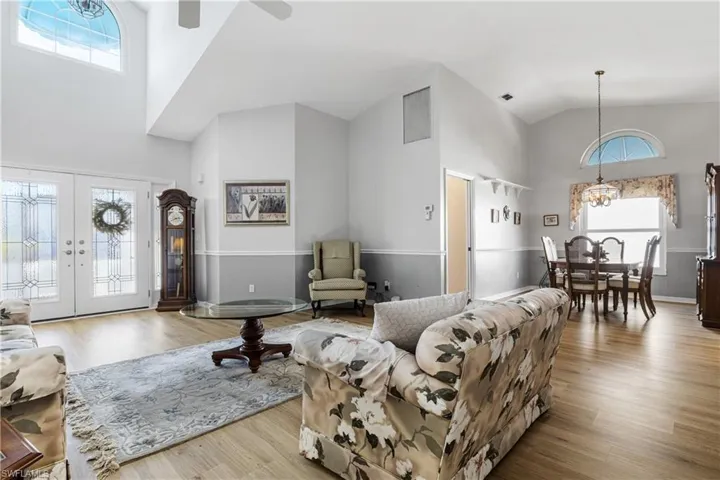 Living room with french doors, high vaulted ceiling, visible vents, and wood finished floors