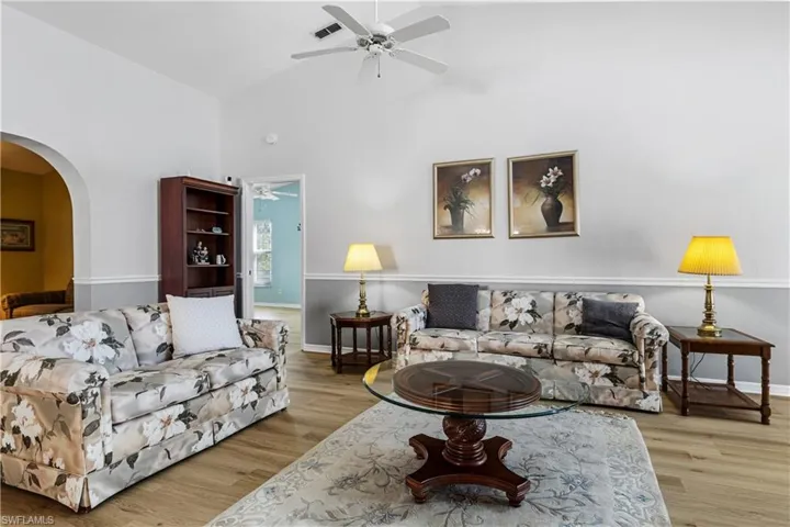 Living area with arched walkways, visible vents, a ceiling fan, and wood finished floors