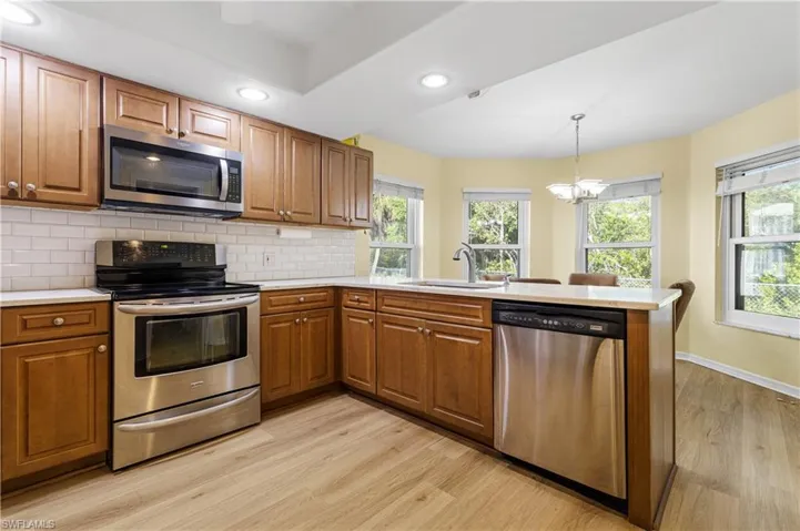 Kitchen with a sink, stainless steel appliances, brown cabinets, and a peninsula