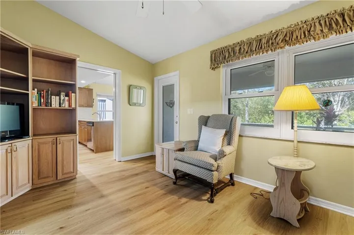 Living area featuring lofted ceiling, baseboards, and light wood finished floors