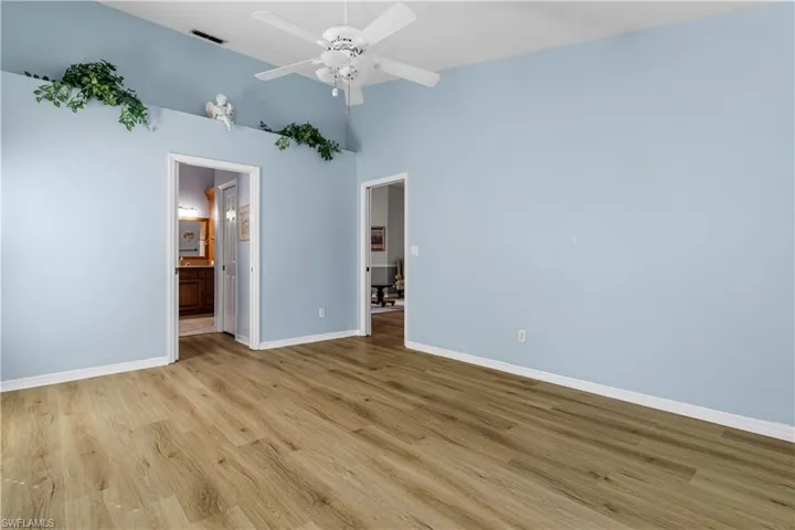 Unfurnished bedroom with light wood finished floors, visible vents, connected bathroom, and baseboards