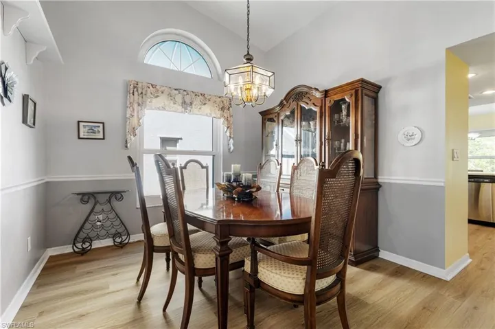 Dining space featuring an inviting chandelier, light wood finished floors, a wealth of natural light, and high vaulted ceiling