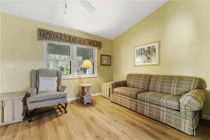 Living room with a ceiling fan, vaulted ceiling, wood finished floors, and baseboards