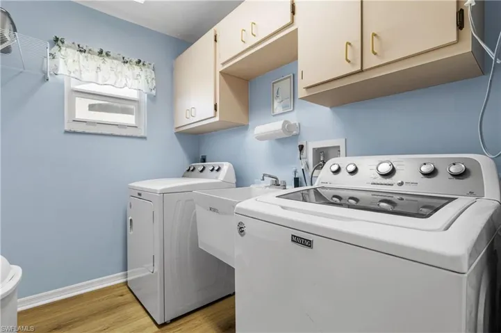 Clothes washing area with light wood-style floors, cabinet space, independent washer and dryer, and baseboards