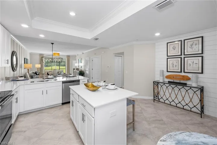Kitchen featuring ornamental molding, a peninsula, visible vents, appliances with stainless steel finishes, and a sink