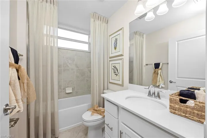 Full bathroom with tile patterned floors, toilet, shower / tub combo with curtain, and vanity