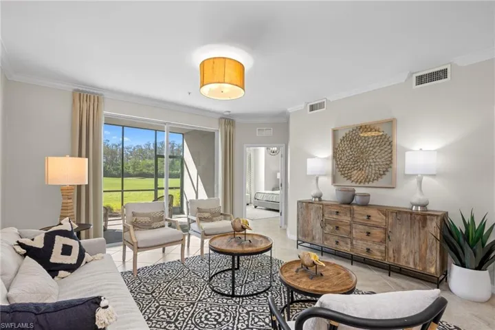 Living room with light tile patterned floors, visible vents, and crown molding