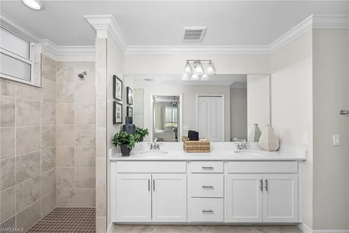 Ensuite bathroom featuring a walk in shower, visible vents, a sink, and ensuite bathroom