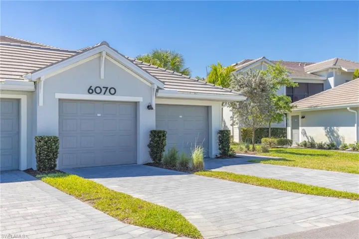 View of front of home with an attached garage, stucco siding, a tile roof, and decorative driveway