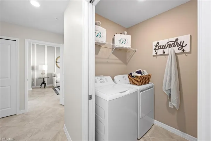 Washroom featuring laundry area, washing machine and clothes dryer, baseboards, and light tile patterned floors