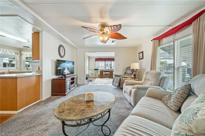 Living room with a ceiling fan, light colored carpet, and a textured ceiling