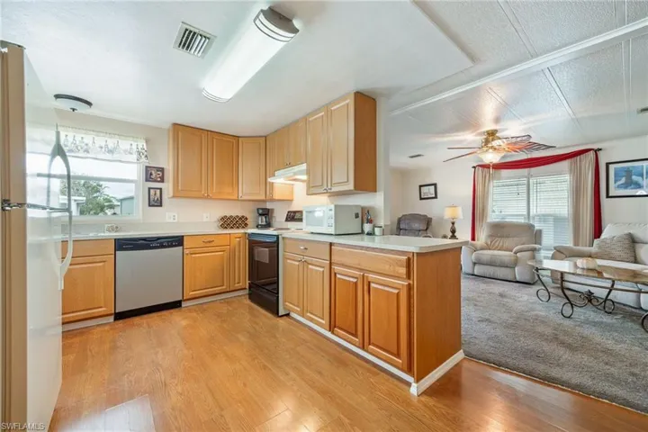Kitchen with light countertops, open floor plan, white appliances, ceiling fan, and light brown cabinets