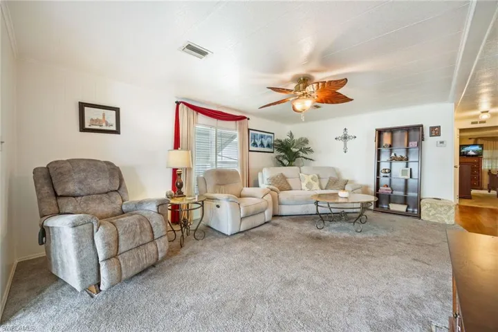 Carpeted living room featuring ceiling fan