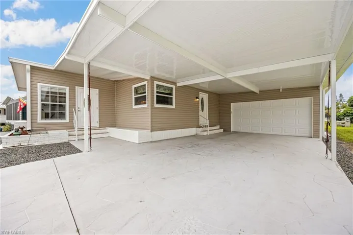 View of front of house featuring entry steps, a garage, a patio, driveway, and an attached carport