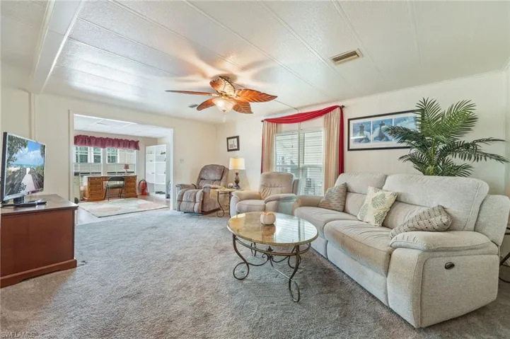 Carpeted living area featuring plenty of natural light and a ceiling fan