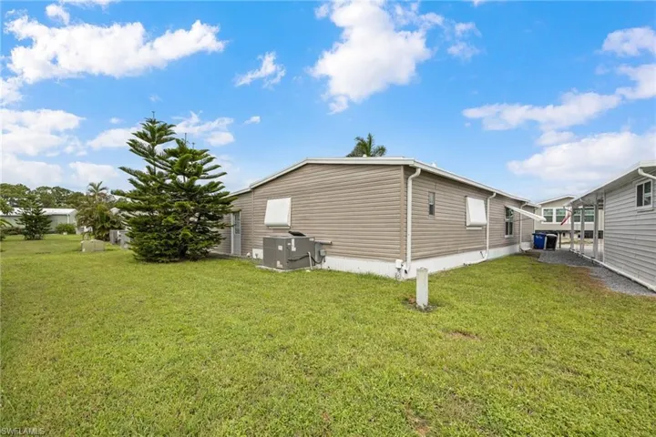 View of side of property featuring a lawn and a cooling unit