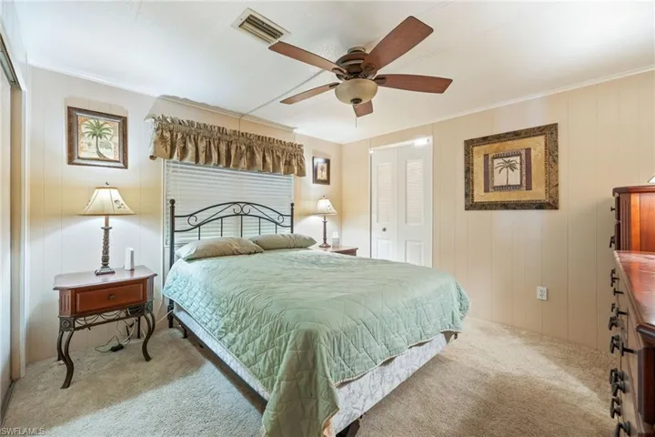 Bedroom featuring a closet, carpet floors, a ceiling fan, wooden walls, and crown molding