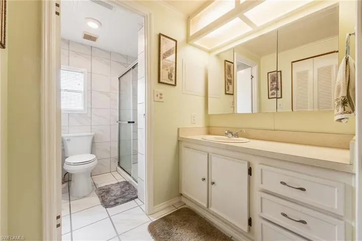 Bathroom with a stall shower, vanity, light tile patterned flooring, and ornamental molding