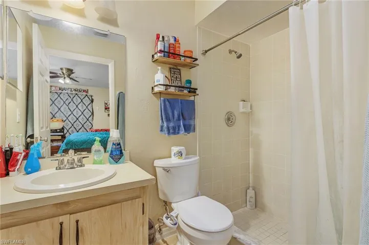 Bathroom with ceiling fan, a shower with curtain, tile patterned flooring, toilet, and vanity