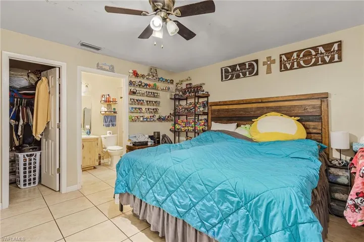 Tiled bedroom featuring ceiling fan and connected bathroom