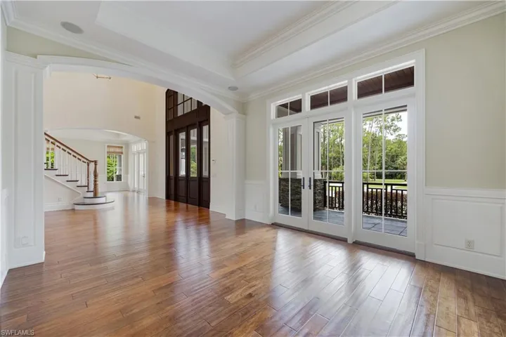 Entrance foyer featuring arched walkways, plenty of natural light, wood finished floors, french doors, and crown molding